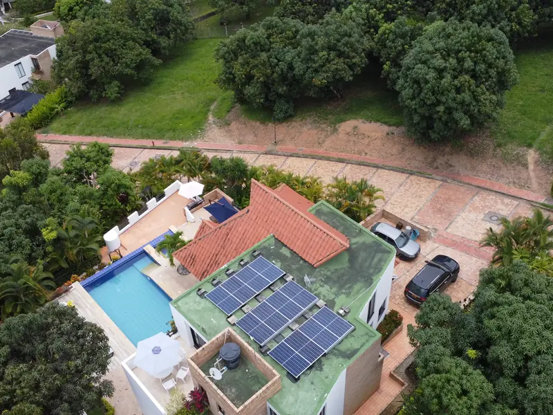 Vista aérea de una casa con techo de teja en Anapoima, Cundinamarca, con paneles solares en la terraza, la piscina y el jardín