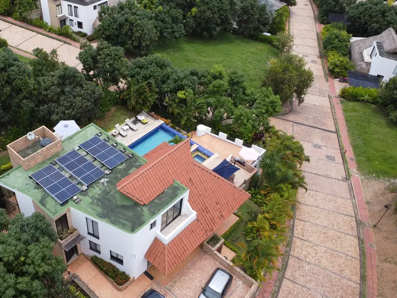 Paneles solares en la terraza de una casa en Anapoima, Cundinamarca, con la piscina y los árboles alrededor