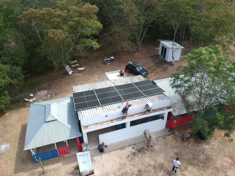 Vista aérea de técnicos trabajando en el techo de una construcción rural con paneles solares en El Plato, Magdalena