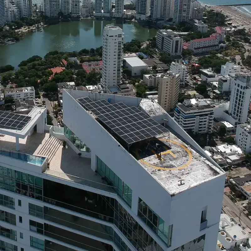 Vista aérea de los paneles solares en el techo del edificio Grand Bay, en Cartagena, con la bahía y los edificios de Bocagrande al fondo