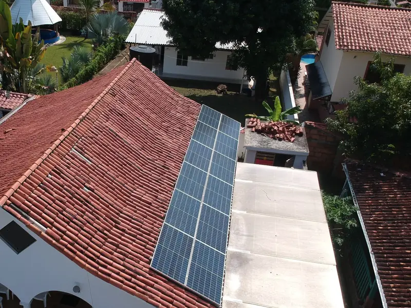 Vista aérea de una casa con techo de teja roja en Melgar, Tolima, con una fila de paneles solares en una cara de la cubierta