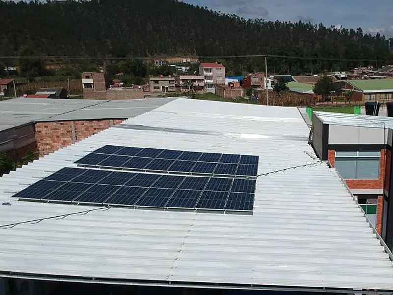 Cubierta metálica de un negocio en Sogamoso, Boyacá, con dos filas de paneles solares y las montañas al fondo